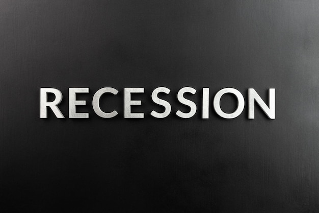 The word recession laid with white brushed metal letters on flat black surface