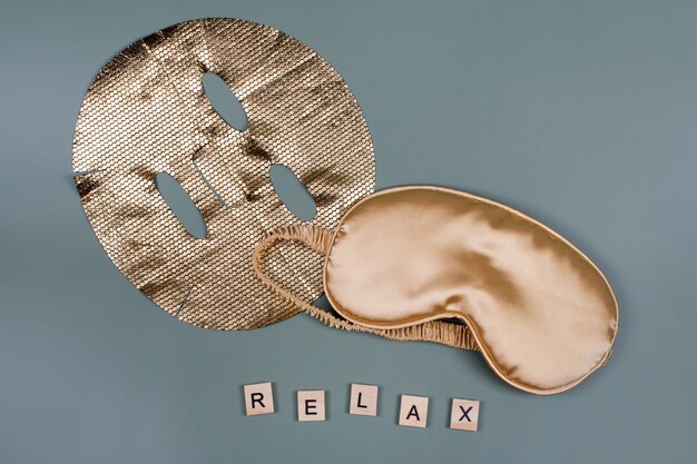 Word RELAX met gouden slaapoogmasker en cosmetisch gezichtsmasker, vlucht- en reisconcept