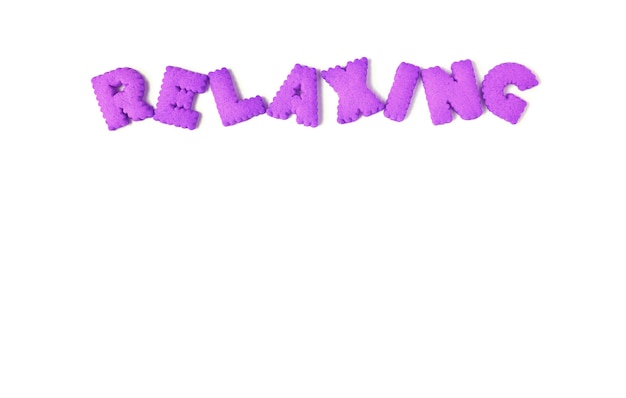 The word RELAXING spelled with purple alphabet shaped biscuits on a white background