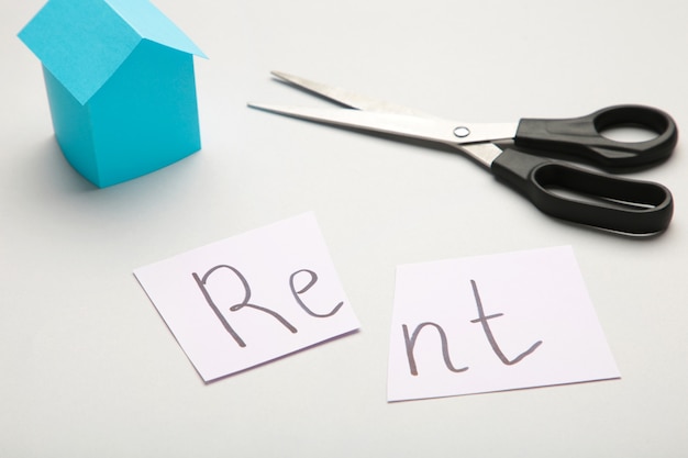 The word 'Rent' written on paper and cut in half with a pair of scissors