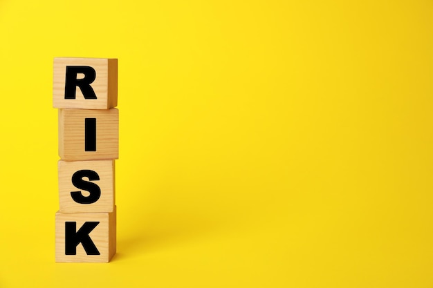 Photo word risk made of wooden cubes on yellow background space for text