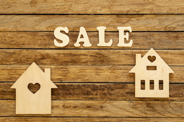 Word Sale made of wooden letters and houses model on a wooden background flat lay