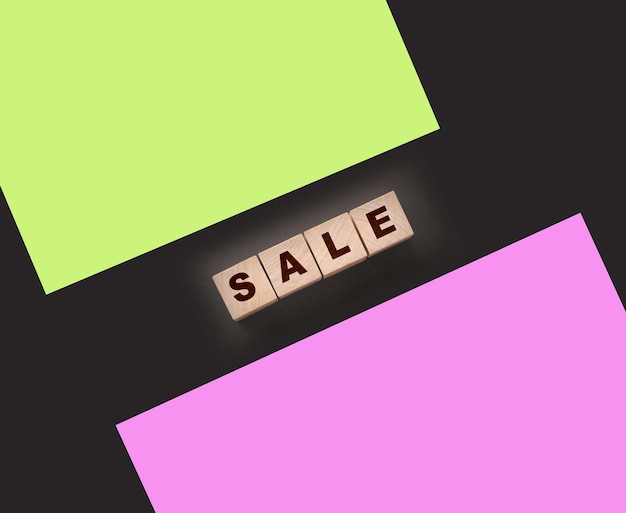 Photo the word sale on wooden cubes on a black background