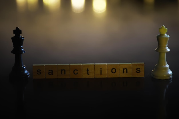 Photo word sanctions made of wooden block letters with dramatic lighting and smoke