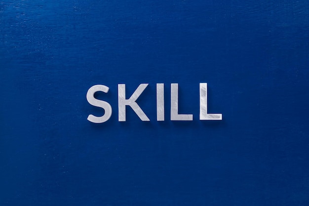 The word skill laid with silver metal letters on classic blue\
board in flat lay with central composition