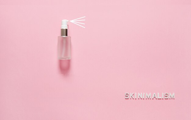 The word Skinimalism and a bottle with a dispenser on a pink background. Close-up, place for your text, mockup