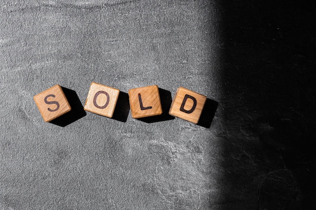 The word sold on wooden cubes on a black background