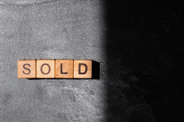 The word sold on wooden cubes on a black background