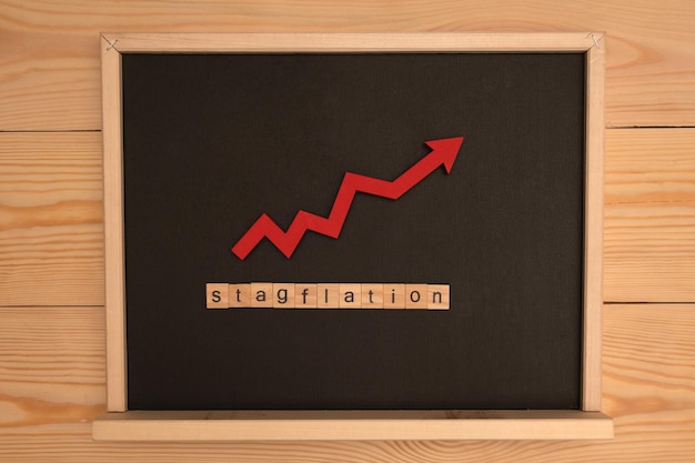 Word stagflation assembled from wooden letters game and red arrow on black school chalkboard