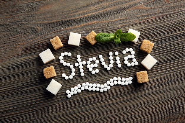 Word Stevia in sugar frame on wooden background