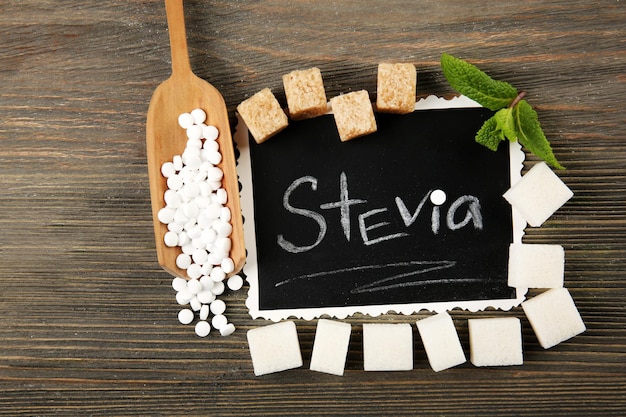 Слово STEVIA написано на черной доске и сахаре на деревянном фоне