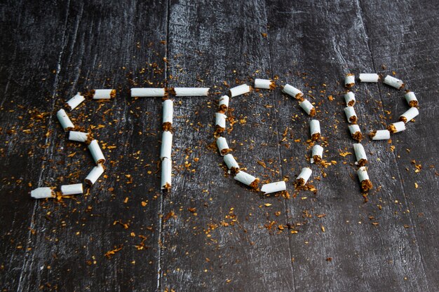 The word stop is written using cigarettes on a dark background. Concept: harm of Smoking, stop Smoking