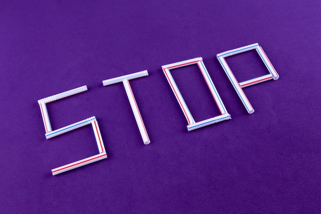 The word STOP made of plastic tubes on purple 