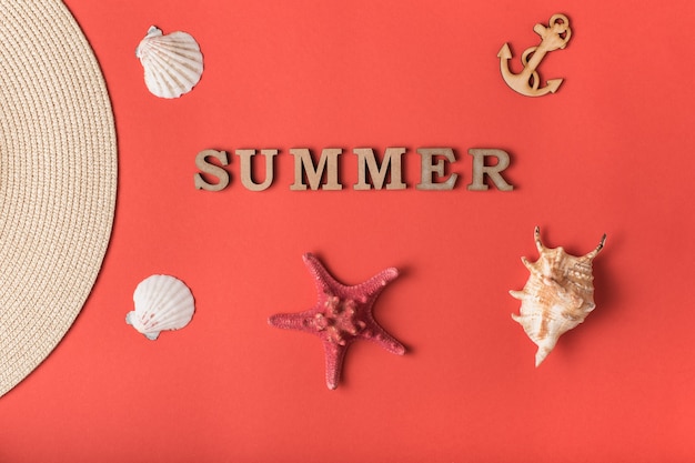 Word Summer from wooden letters. Seashells, anchor and part of a hat. Live coral background.