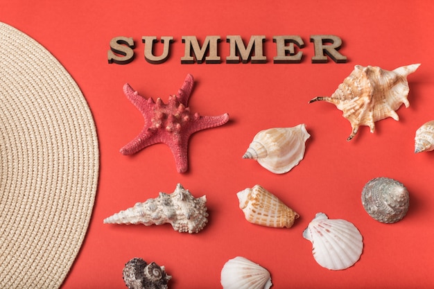 Word Summer from wooden letters. Seashells, part of a hat and a live coral background