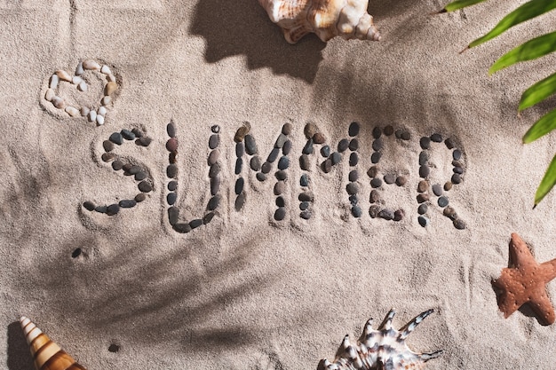 Photo the word summer is laid out with stones on a sandy summer beach among seashells