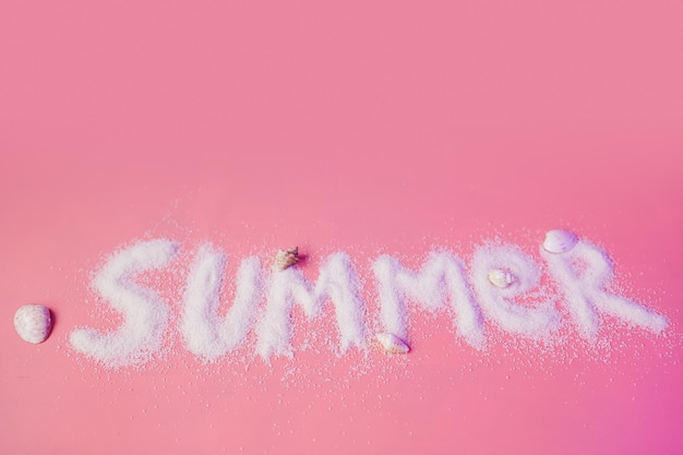 Слово лето из песка на розовом фоне