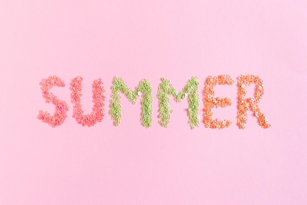 Фото Слово лето из разноцветных блесток звезд на розовом пастельном фоне
