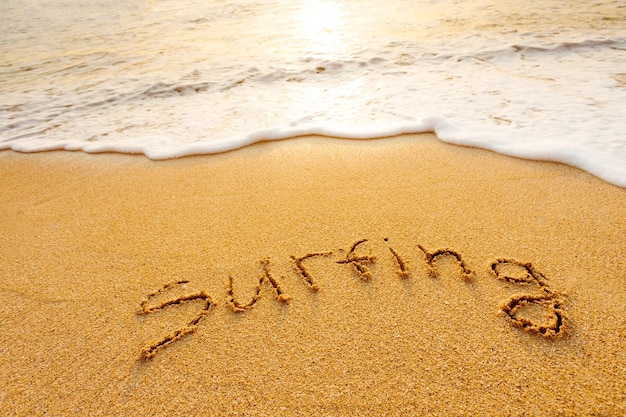 The word Surfing written in the sand on beach