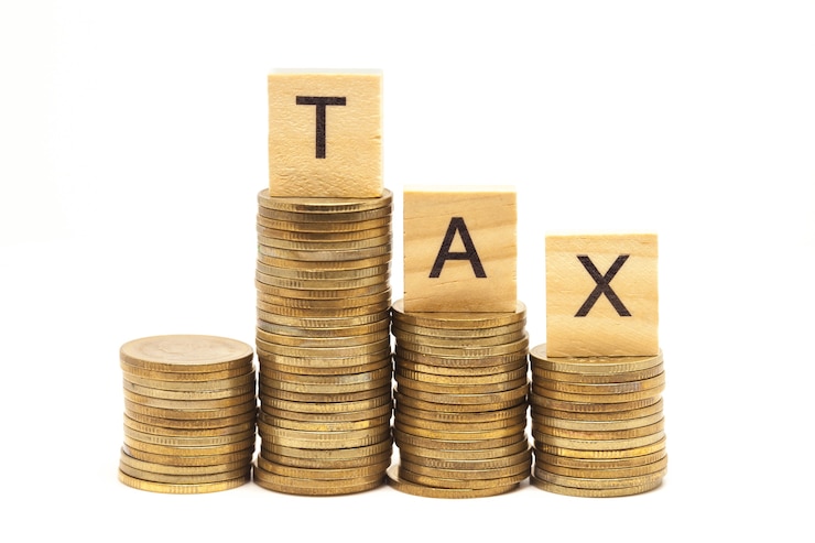 Photo word tax concept on wooden block over on stacked coins