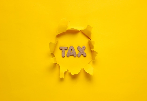 The word tax in a torn hole of yellow surface. 