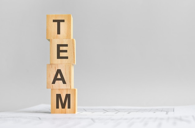 Word team with wood building blocks, light gray background. document with numbers on background, business concept. space for text in right. front view.