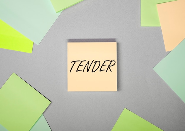 Word tender on sticky note on gray background with colorful papers