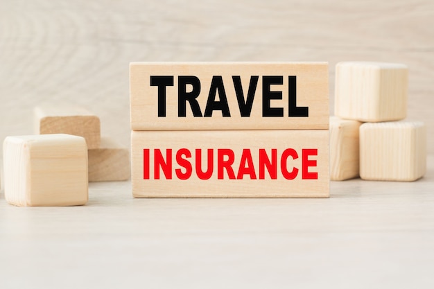 Слово TRAVEL INSURANCE написано на деревянной конструкции из кубиков.