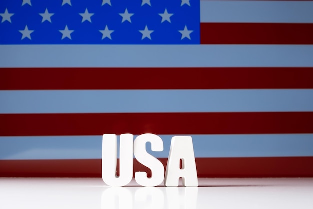 Word usa made from white concrete letters on the background of\
the flag of usa