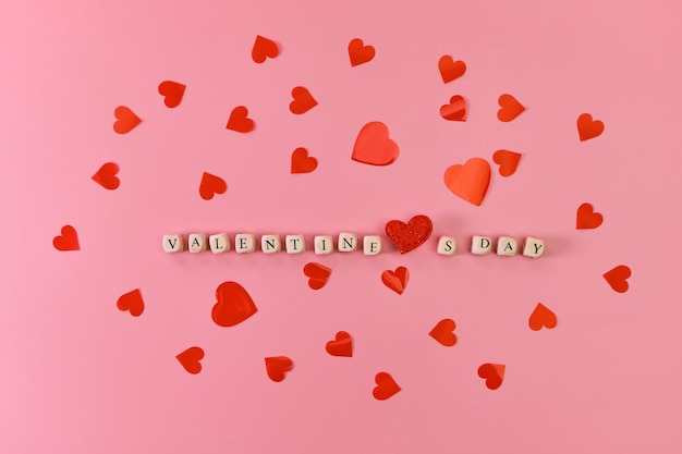 The word Valentine's Day and red hearts. Love on wooden blocks. Love theme. Wooden beads for letters. Love, positive emotions. Wooden cubes with letters.