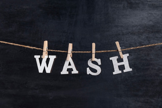 Word WASSEN met wasknijpers op zwarte achtergrond. Concept van wasservice.