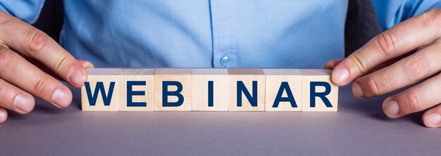 Слово WEBINAR составлено из деревянных кубиков человеком.