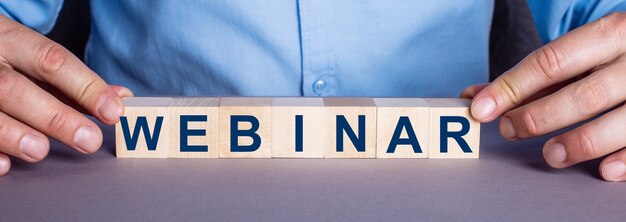 The word WEBINAR is made up of wooden cubes by a man