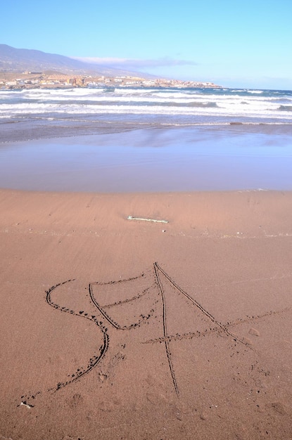 Слово, написанное на песке тропического пляжа