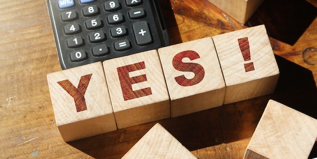 The word Yes on wooden blocks and calculator Business motivation and education concept