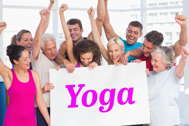 Foto la parola yoga e le persone entusiaste che tengono un cartellone bianco in palestra contro il design dell'onda bianca