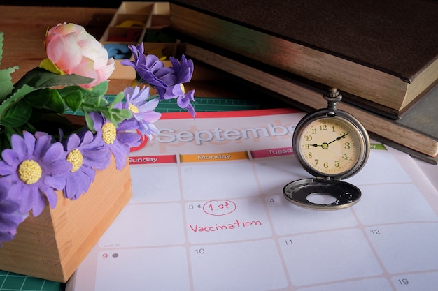 Foto formulazione vaccinaton sul calendario con orologio da tasca vintage, appuntamento per la salute.