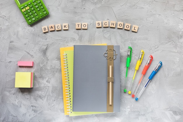 Parole torna al quaderno di scuola e alle penne su uno sfondo grigio