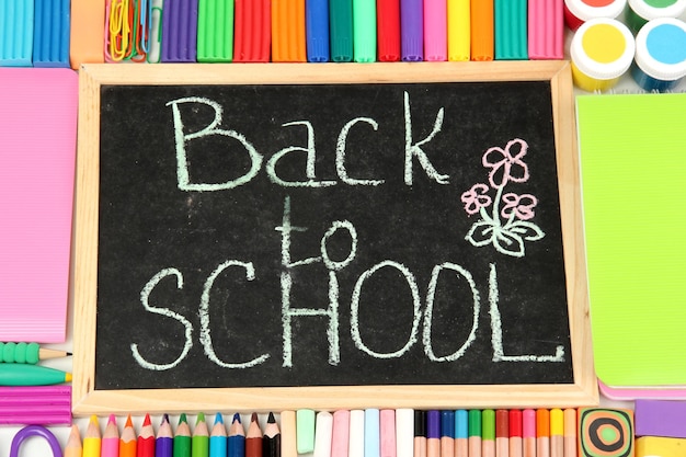 小さな学校の机に"Back to School"という言葉がチョークで書かれていて,様々な学校用品が近くに描かれています.