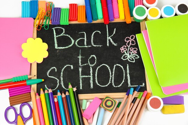 the words back to school written in chalk on the small school desk with various school supplies closeup