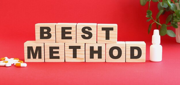 BESTMETHODという言葉は赤い背景の木製の立方体でできています。