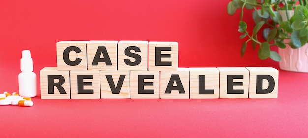 CASE REVEALEDという言葉は、赤い背景に医薬品が入った木製の立方体でできています。