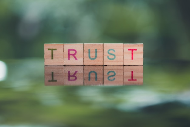 Words concept TRUST word cube on reflection floor bokeh blur background