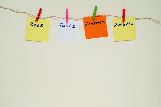 Words Goal, Tasks, Finance, Results on multicolored paper stickers with clothespins on a rope. Copy space