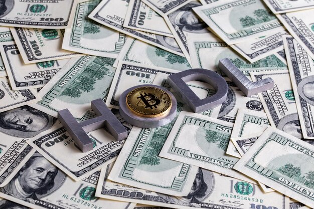The words HODL laid with aluminium letters and bitcoin shiner on the US dollar banknotes background with selective focus and diagonal composition