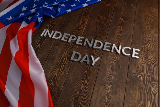 独立記念日という言葉は、しわくちゃのアメリカ合衆国の旗が付いた茶色の木の板の表面に置かれました
