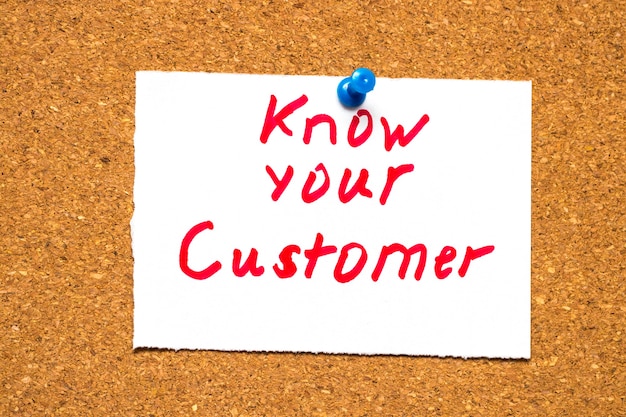 The words know your customer on a note card pinned to a cork
notice board as a reminder to research your market in business