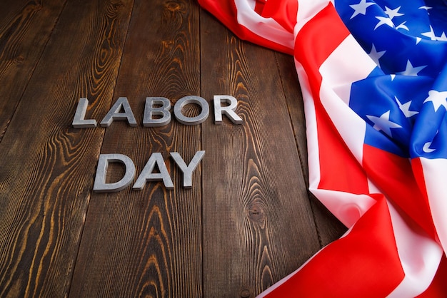 Photo words labor day laid with silver metal letters on wooden surface with crumpled usa flag on left side