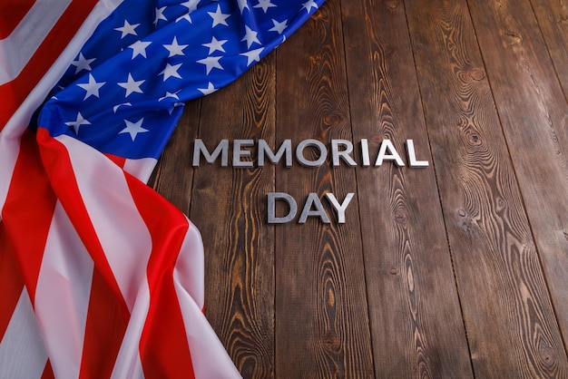 Foto le parole memorial day posate con lettere in metallo argentato su una superficie di legno con bandiera usa sgualcita