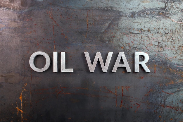 Words oil war laid in line with silver metal letters on rusted heavy hot rolled uncoated steel sheet surface directly above